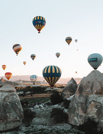 Vibrant hot air balloons soaring over the unique rock formations of Cappadocia at sunrise. HD phone wallpaper