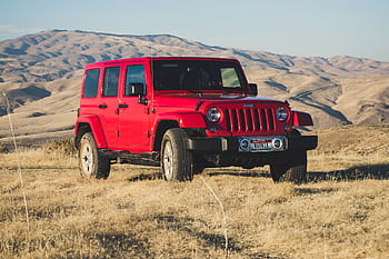 A striking red Jeep Wrangler parked in a vast, desert-like landscape under a clear sky. HD wallpaper