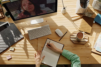 A student taking notes during a video call for online learning at home. HD wallpaper