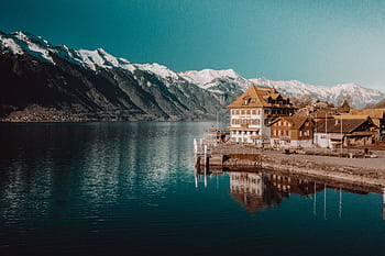 Charming Swiss village by a tranquil lake with stunning snowy mountain backdrop. HD wallpaper