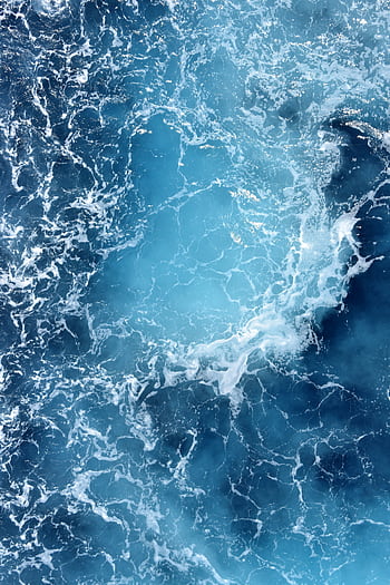 High angle shot of swirling turquoise ocean waves creating a dynamic seascape pattern. HD phone wallpaper