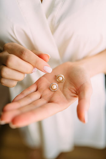 Close-up of elegant pearl earrings held in a hand, showcasing luxury jewelry. HD phone wallpaper