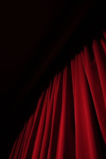 A striking red velvet curtain with dramatic lighting in a theater setting, offering ample copy space. HD phone wallpaper