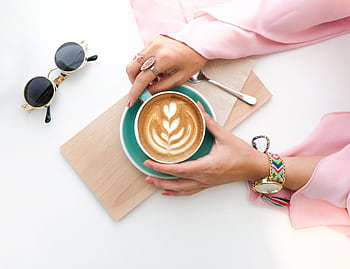 Stylish latte art with a woman's hands in a pink top, accessorized with jewelry and sunglasses. HD wallpaper
