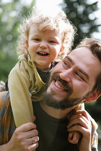 A joyful moment captured with a father and his son smiling in an outdoor setting. HD phone wallpaper