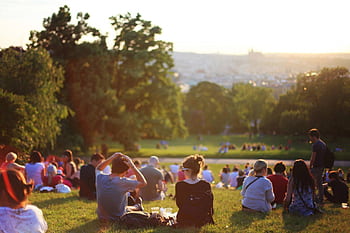 People relaxing and enjoying a sunny day in a bustling city park. HD wallpaper