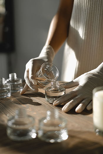 Faceless woman in a workshop bottling essential oils with precision and care. HD phone wallpaper