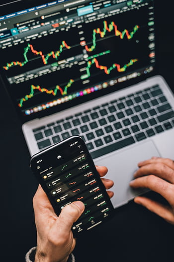 Person analyzing stock market data with a laptop and smart showing trading graphs. HD phone wallpaper
