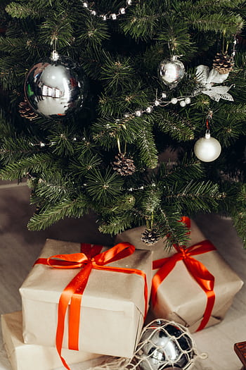 Festive Christmas tree adorned with silver ornaments and gifts wrapped in red ribbon. HD phone wallpaper