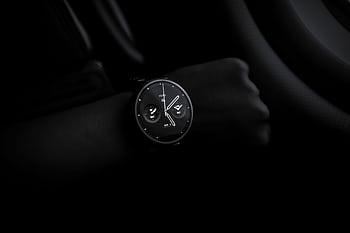 A sleek Moto 360 smartwatch showing time on a wrist in a dimly lit setting, emphasizing its modern design and technology. HD wallpaper