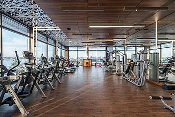 Spacious gym interior featuring modern equipment and large windows. HD wallpaper