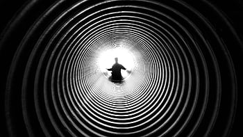 A person silhouetted against light at the end of a spiral tunnel, creating a striking black and white contrast. HD wallpaper