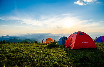 Vibrant tents on a grassy mountain ridge with a stunning sunrise view, ideal for adventure. HD wallpaper