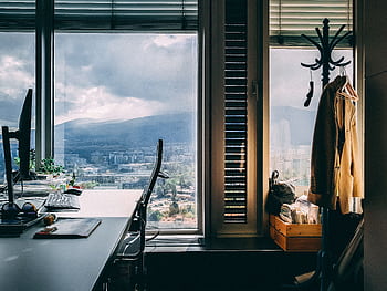 A contemporary office setting with a stunning mountain view through large windows and stylish furnishings. HD wallpaper
