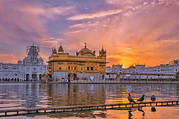 Stunning sunset view of the Golden Temple in Amritsar, reflecting in the water with vibrant skies. HD wallpaper