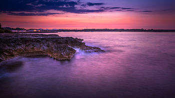 Rocks Sea Coast And Landscape View Of Buildings Under Purple Sky During Sunset Nature HD wallpaper