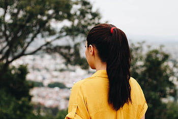 A woman in a yellow shirt with a ponytail views a cityscape from a park. HD wallpaper