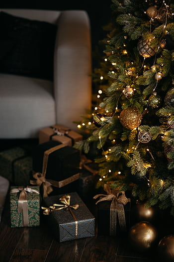 Cozy Christmas scene with a beautifully decorated tree and elegant wrapped presents around an armchair. HD phone wallpaper