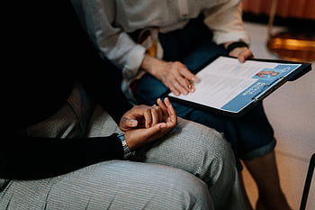 Two professionals reviewing a resume in an office setting, focused on teamwork. HD wallpaper