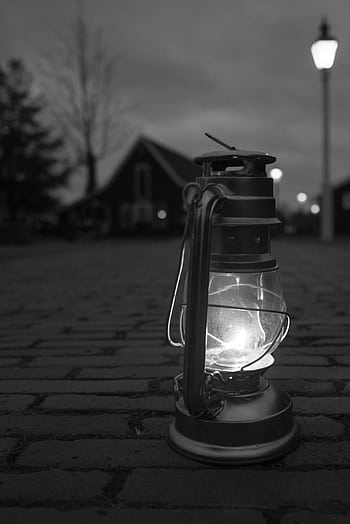 A vintage lantern illuminates a cobblestone street at night, creating a nostalgic urban scene. HD phone wallpaper