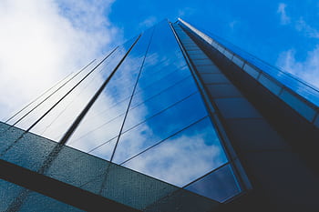 Dramatic low angle view of a modern skyscraper reflecting the blue sky. HD wallpaper