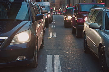 A congested city street lined with cars stuck in traffic at dusk, showcasing urban life. HD wallpaper