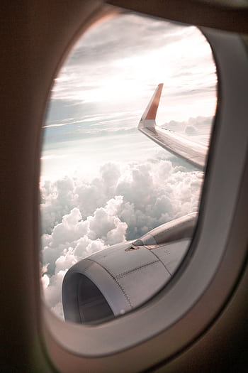 View of clouds and airplane wing from a window seat, depicting a serene flying experience. HD phone wallpaper