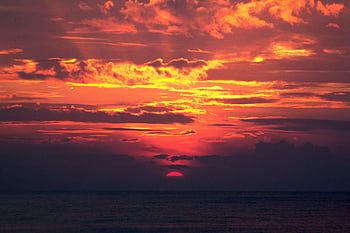 A breathtaking sunset over the ocean with vivid orange and red clouds, ideal for backgrounds. HD wallpaper