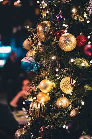 Close-up of a Christmas tree adorned with vibrant ornaments and lights. HD phone wallpaper