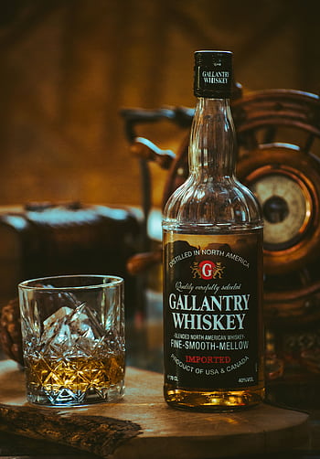 Close-up of Gallantry Whiskey bottle with glass on wooden surface, warm lighting. HD phone wallpaper
