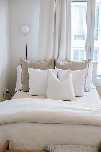 A serene, stylish bedroom showcasing a cozy bed with soft pillows and neutral decor. HD phone wallpaper