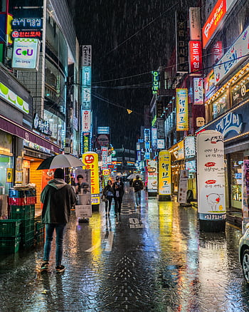 Colorful neon-lit street in Seoul, South Korea showing bustling nightlife with reflections on wet pavement. HD phone wallpaper