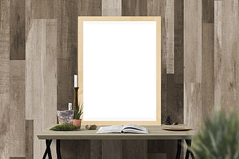 Cozy indoor setting with a blank frame for artwork surrounded by decor on a wooden table against a textured wall. HD wallpaper