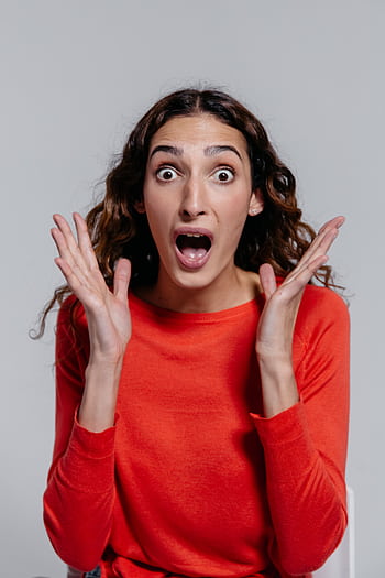 Portrait of a surprised woman with hands raised, showcasing a shocked facial expression. HD phone wallpaper