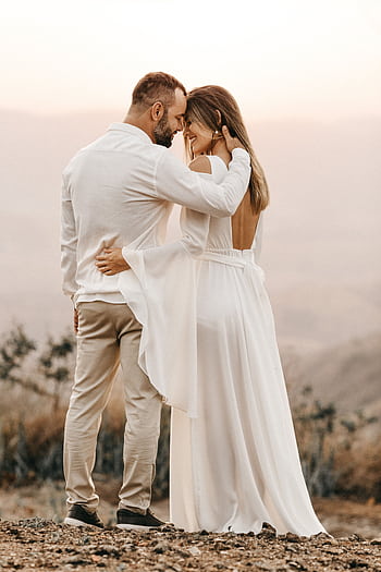 A bride and groom embracing in a serene outdoor setting, symbolizing love and unity. HD phone wallpaper