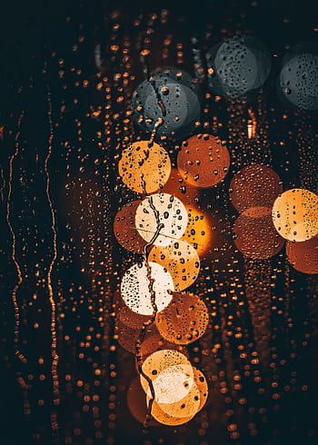 Abstract view of colorful bokeh lights through a rainy window, creating a warm, moody atmosphere. HD phone wallpaper