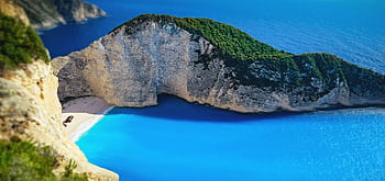 A breathtaking aerial view of Navagio Beach in Zakynthos, Greece with turquoise waters and dramatic cliffs. HD wallpaper