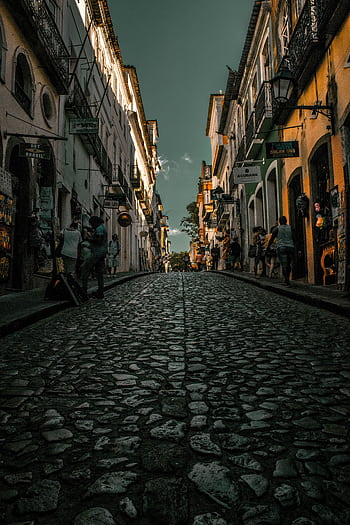 Explore historic cobblestone streets lined with lit buildings in an enchanting evening setting. HD phone wallpaper