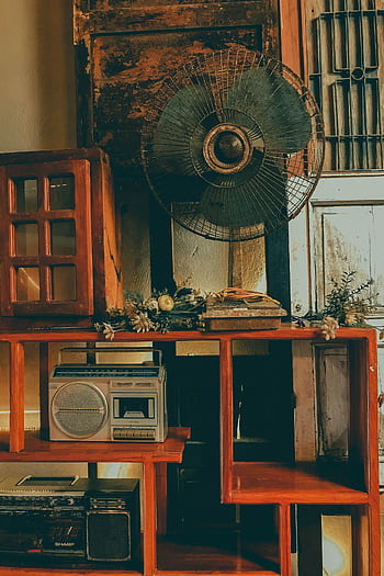 A nostalgic look into vintage Vietnamese living room decor featuring an old fan, radio, and wooden furniture. HD phone wallpaper
