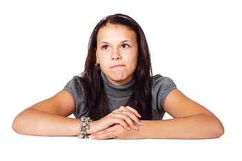 A young woman with a pensive expression sits thoughtfully against a white background, conveying introspection. HD wallpaper