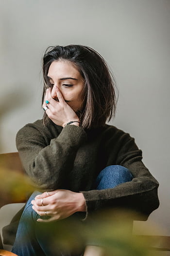 A woman in a moment of contemplation sitting indoors, conveying solitude and introspection. HD phone wallpaper
