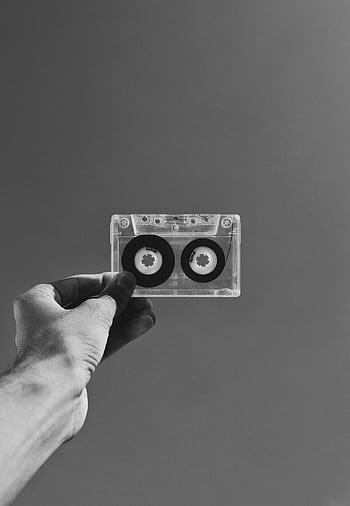 Hand holding a classic cassette against a plain backdrop in black and white. HD phone wallpaper