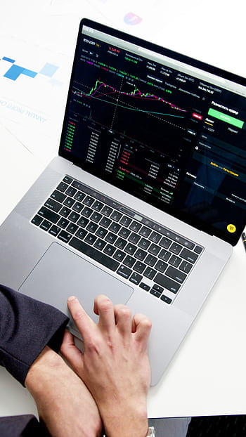 Professional analyzing stock market graphs on a laptop, showcasing investment insights. HD phone wallpaper