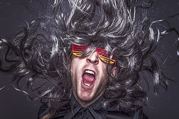 Vibrant portrait of a man with wild hair and colorful sunglasses expressing energy and fun. HD wallpaper