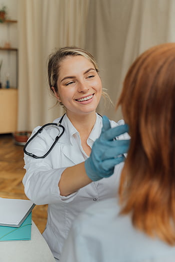 A cheerful healthcare professional examining a patient indoors, promoting positive healthcare experiences. HD phone wallpaper