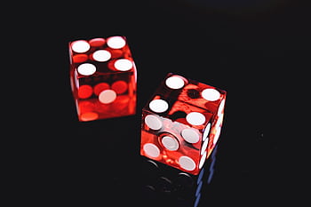 Close-up of two red dice on a shiny black background symbolizing luck and chance. HD wallpaper
