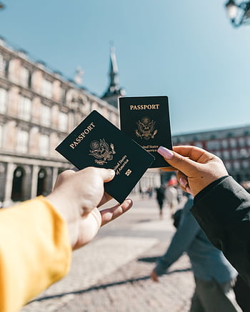 Travelers holding US passports at Plaza Mayor, Madrid, highlighting tourism and exploration. HD phone wallpaper