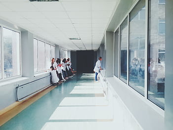 A brightly lit hospital hallway with medical staff in white coats, conveying a professional healthcare environment. HD wallpaper