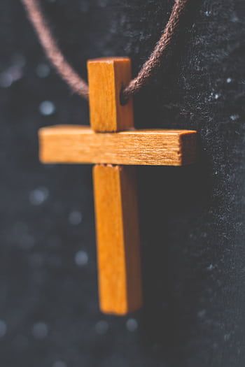 Detailed close-up of a hanging wooden cross necklace on a fabric background. HD phone wallpaper