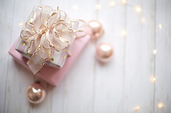 Top view of a beautifully wrapped gift with rose gold ornaments and soft lighting, perfect for celebrations. HD wallpaper